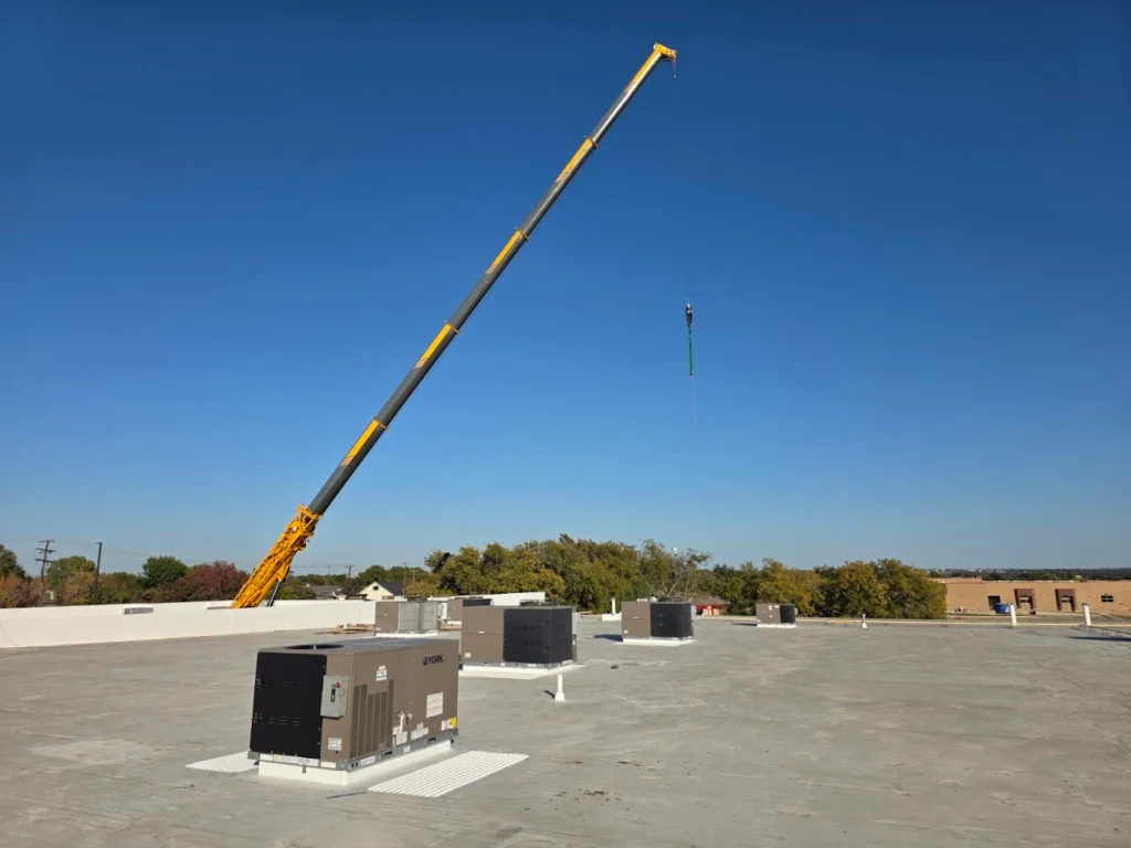 Commercial rooftop HVAC units with a crane in the background